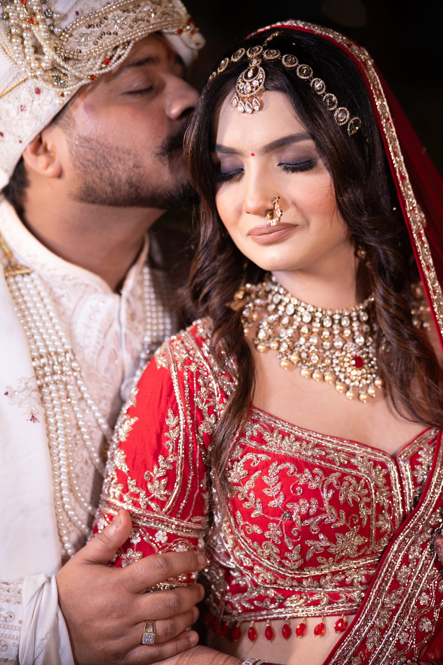 Bride and groom sharing a romantic moment in traditional Indian wedding attire