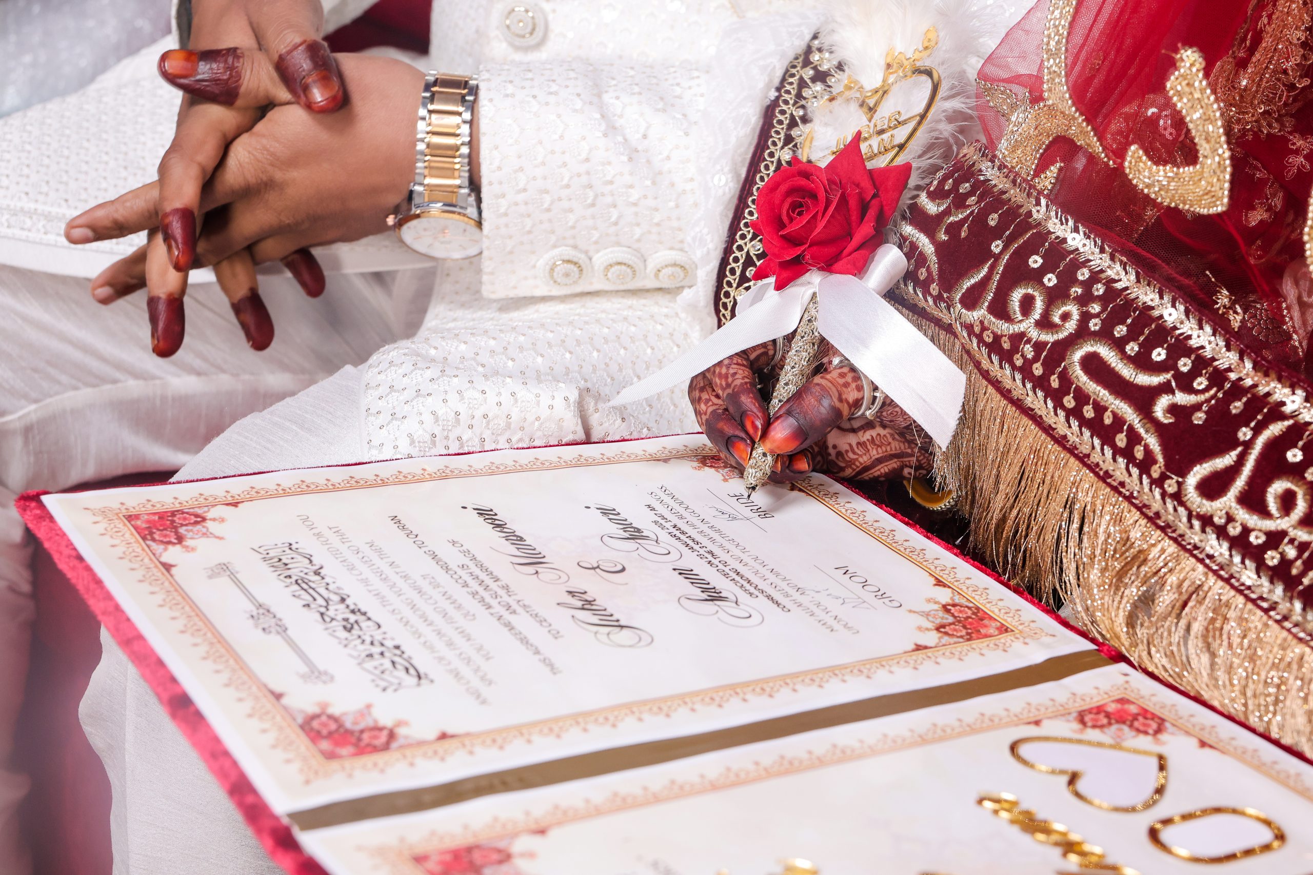 Wedding invitation and red floral decoration arranged on a white surface
