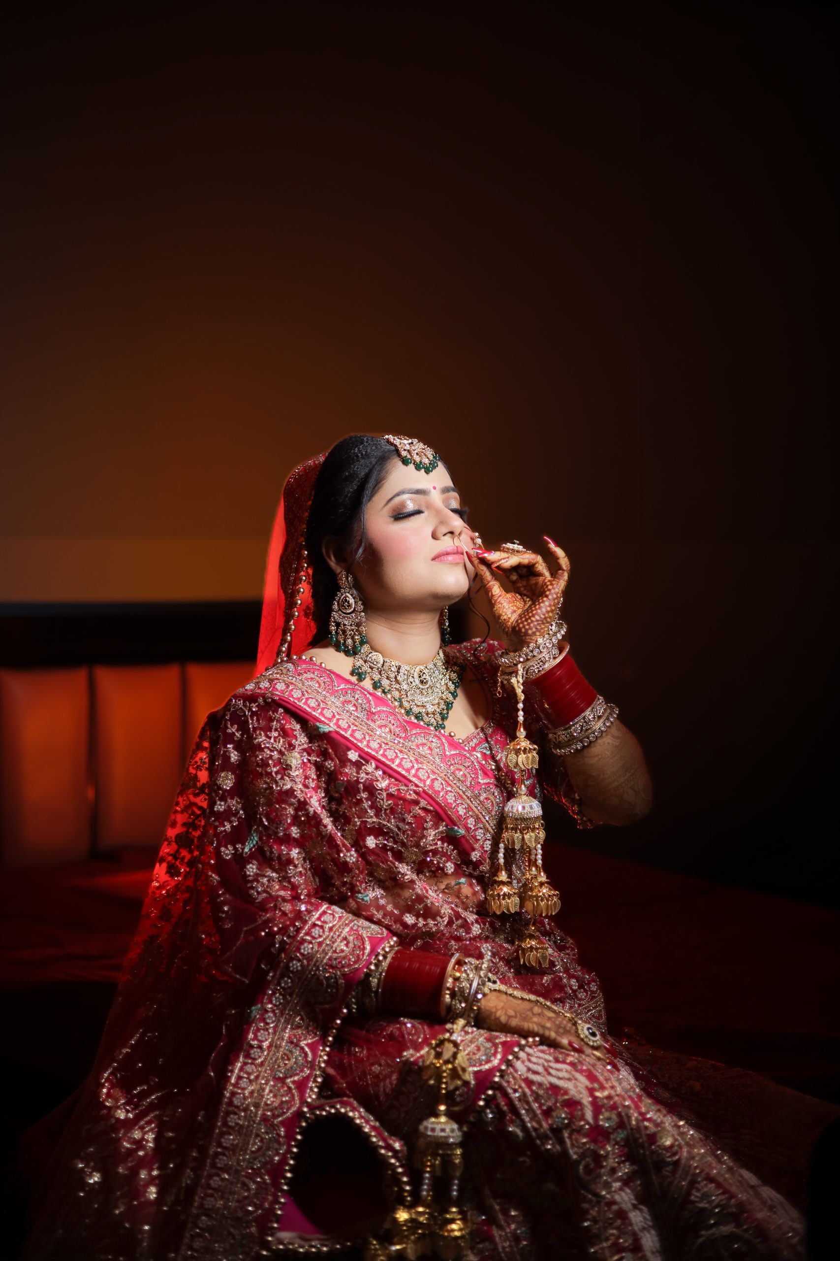 Woman in red wedding attire holding a glass during an indoor photoshoot