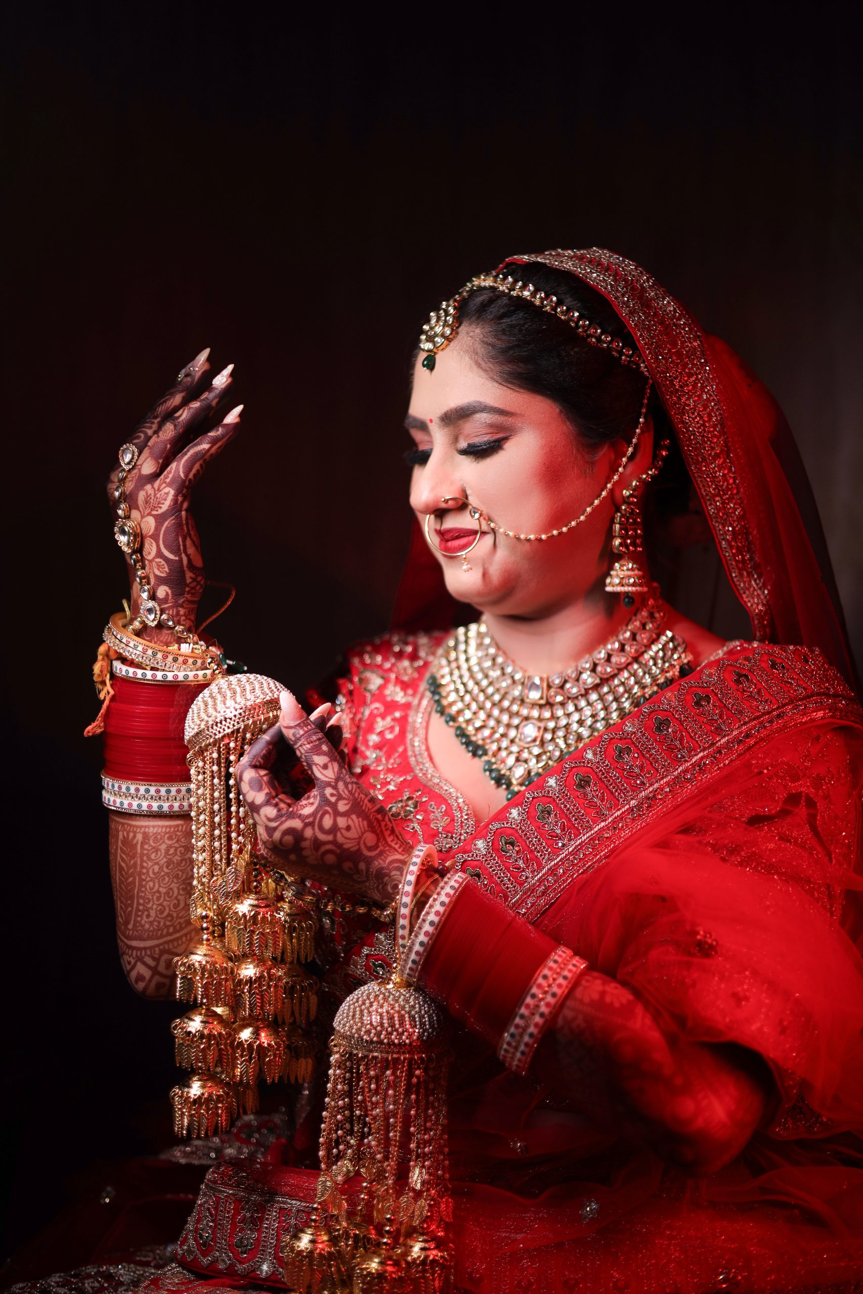Woman wearing a red veil, gold jewelry and detailed wedding makeup