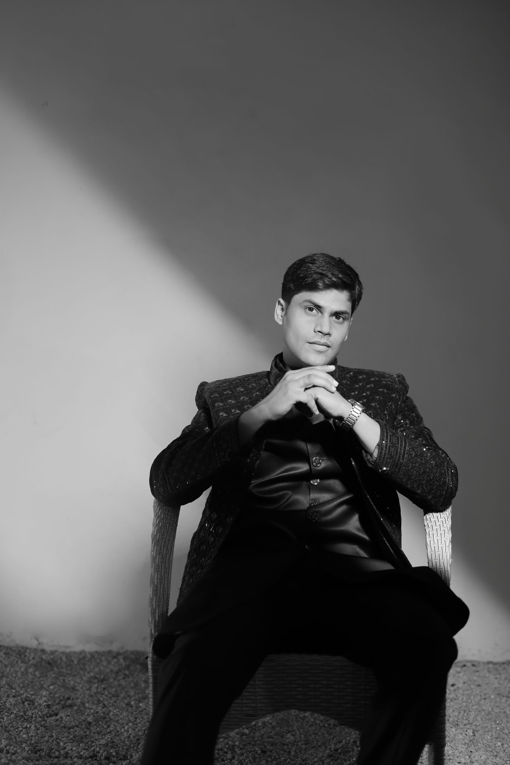 Groom adjusting his dark wedding sherwani in a black and white portrait