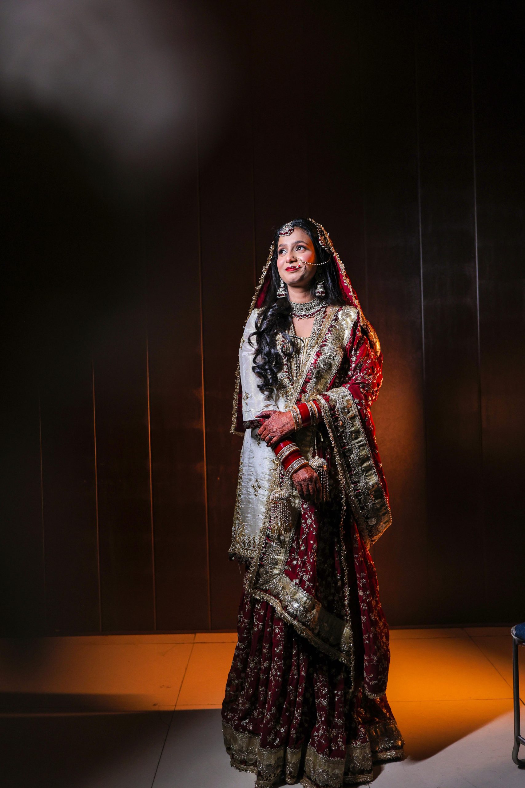 Bride standing in traditional wedding attire in a softly lit setting