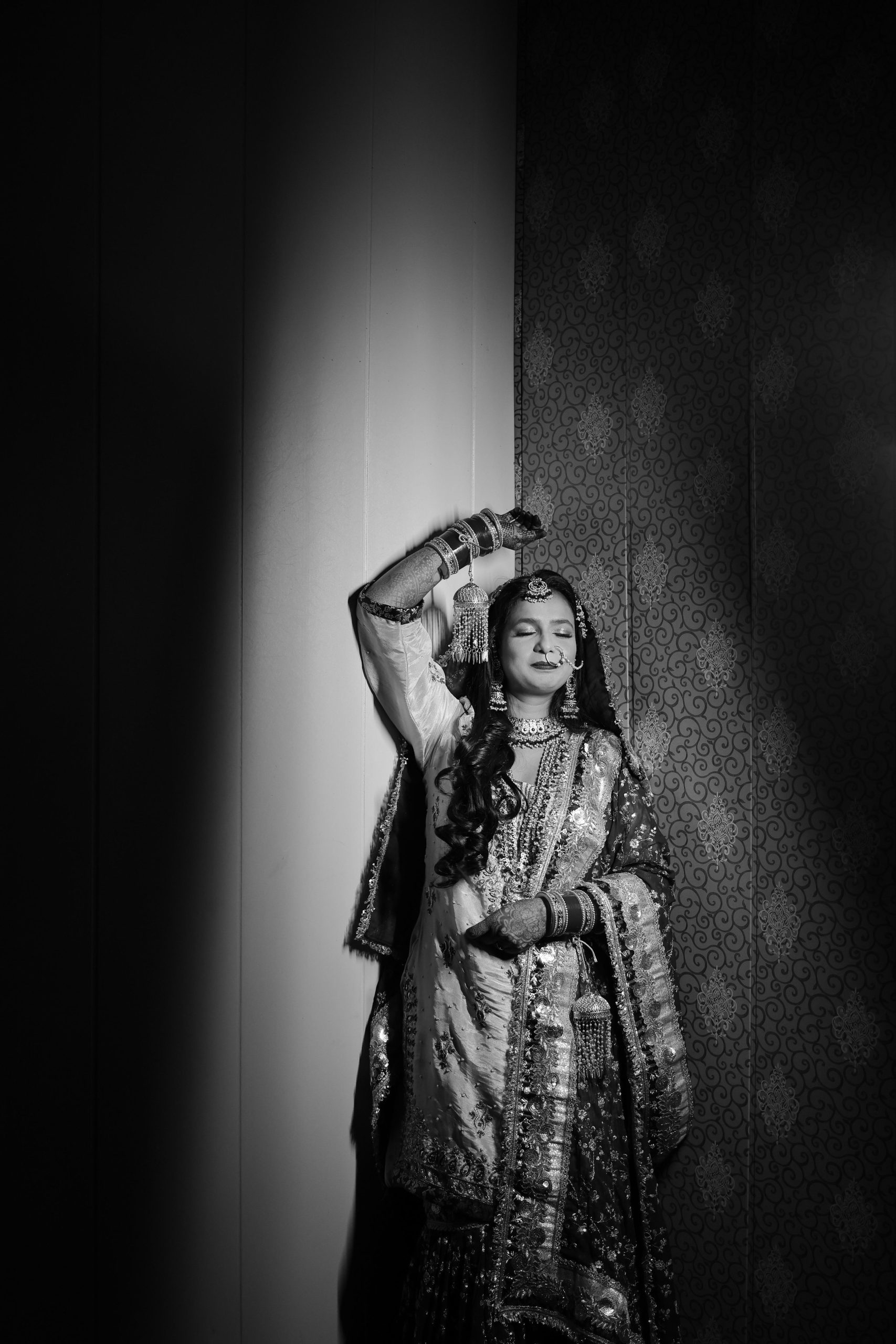 Bride posing with one arm raised in an artistic black and white portrait