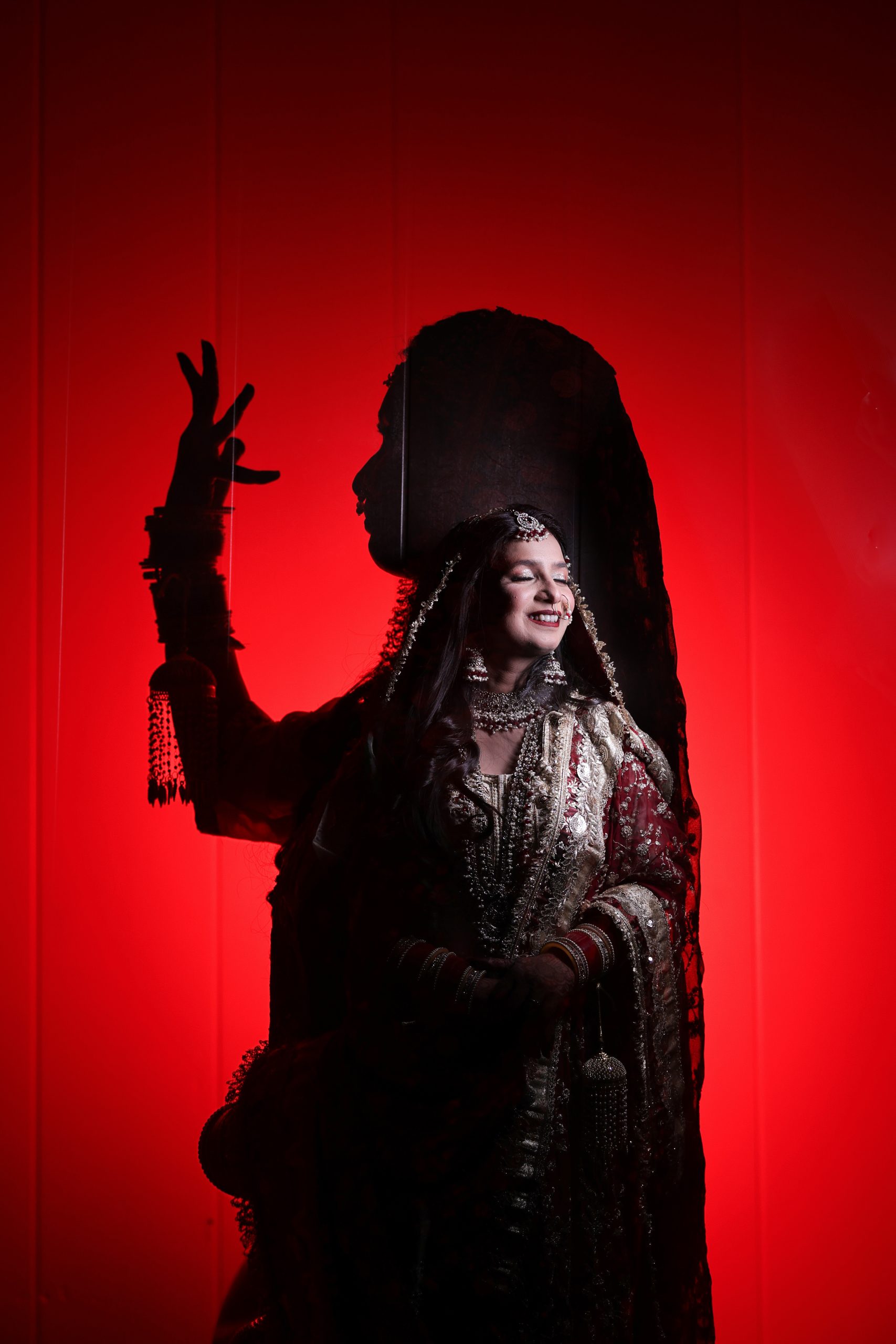 Bride posing in silhouette against dramatic red wedding lighting