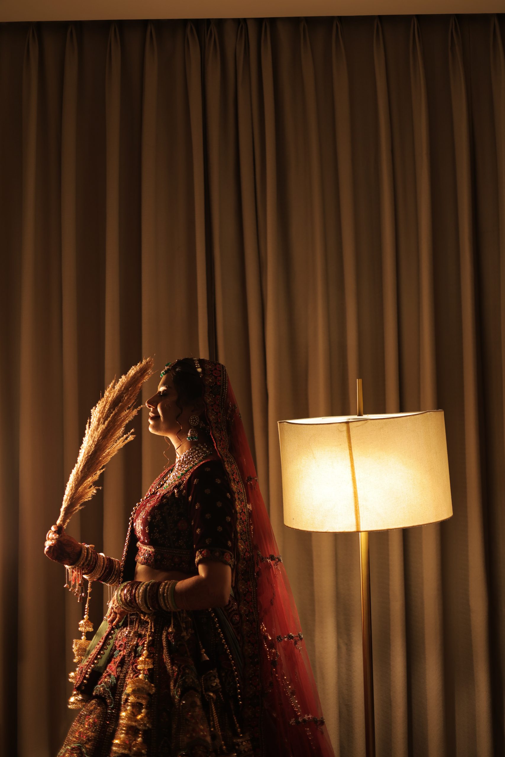 Bride posing near golden curtains under warm wedding lighting