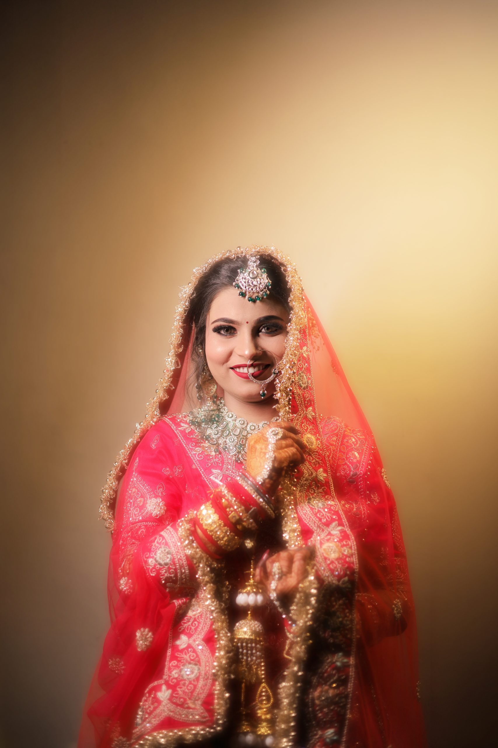 Indian bride wearing a red lehenga in a warm-lit portrait